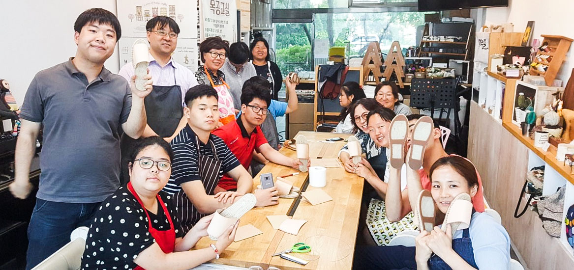직업훈련 공방 빼무락에서 직접 만든 신발을 들어 보이는 참여자들